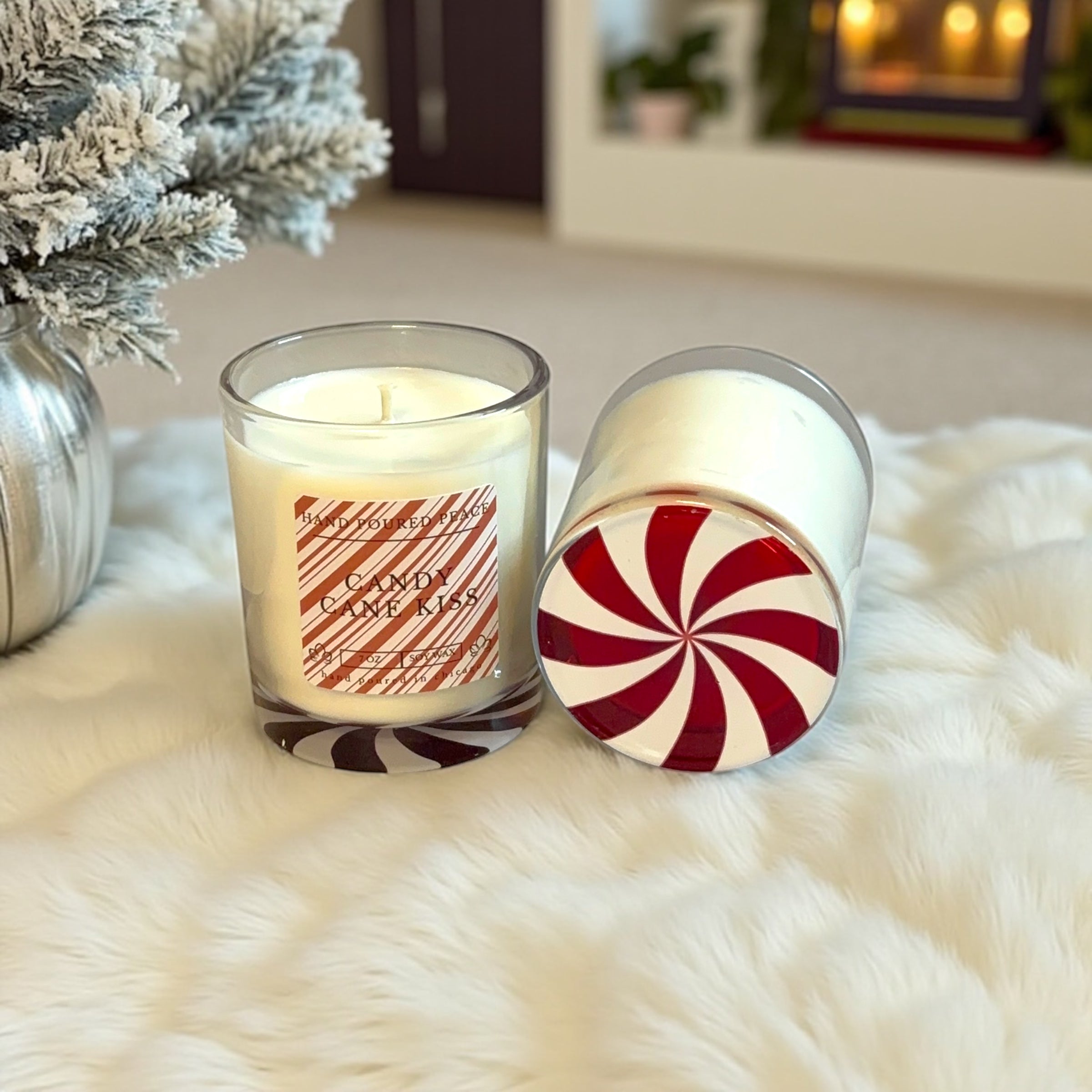 Two candles with peppermint-themed designs on a fluffy white surface.