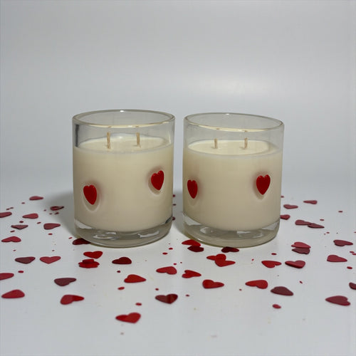 Two candles with red heart decorations on a white background with scattered red hearts.
